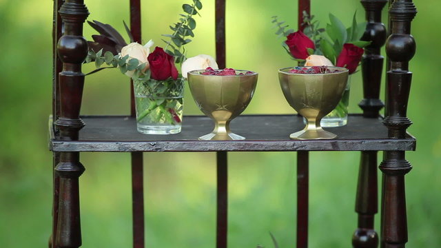 On the antique wooden stand tiny bouquets of roses and wedding cake
