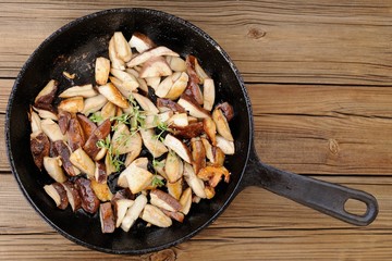 Fried porcini mushrooms with fresh thyme in cast iron skillet on