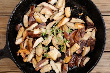 Fried porcini mushrooms with fresh thyme in cast iron skillet on