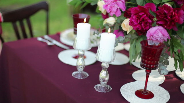 Wedding table decor at the nature with lighted candles, close-up. Steadicam shot