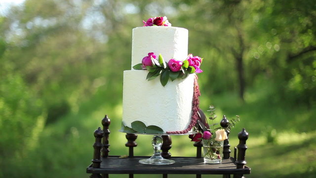 On the antique wooden stand beautiful wedding cake in the sunlight