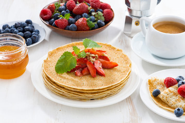 crepes with strawberry, jams and honey on white table