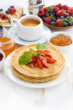 crepes with strawberry, jams and honey on white background