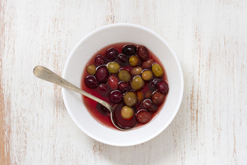 olives in white dish with spoon on white wooden background