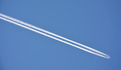 Condensation trace left from a 4-engine airplane on blue sky