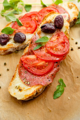 Bruschetta with tomatoes, salami, mozzarella cheese and olives