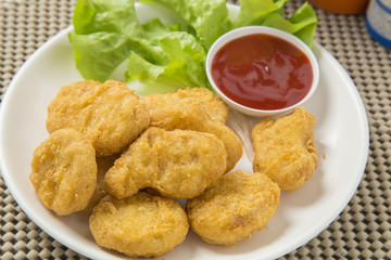 A pile of chicken nuggets on white plate with sauce