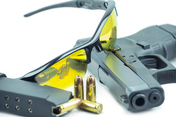 Naklejka premium Orange sun glasses and 9mm black gun pistol isolated on white background.