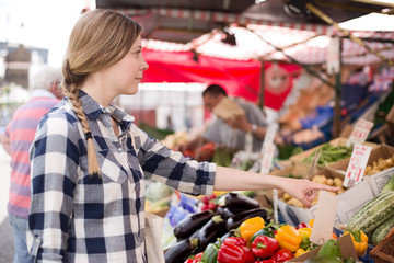 young woman showing a market trader what she wants.
