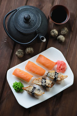 Sushi set with a dip sauce and tea over dark wooden background