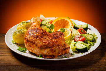 Barbecued chicken leg with boiled potatoes and vegetables