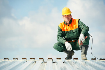 Worker builder roofer at metal profile work - obrazy, fototapety, plakaty