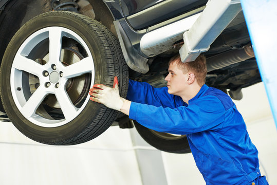 auto mechanic inspecting car wheel 
