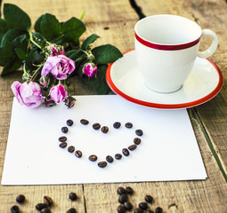 coffee cuo, coffee beans and roses on wooden background