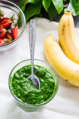 Green smoothie with spinach, kiwi, banana and mint in a glass, d