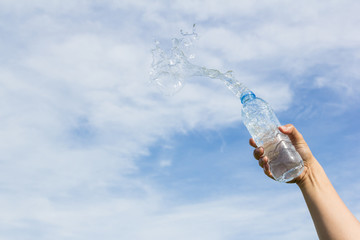 hand holding water bottle on sky background