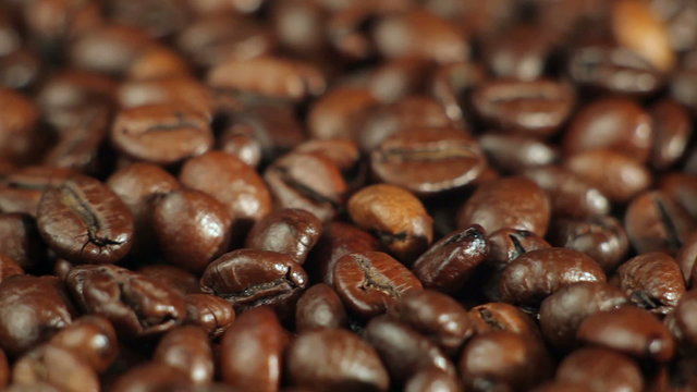 Roasted coffee beans rotates on the table. close-up