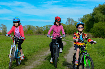 Happy mother and kids on bikes cycling outdoors, active family sport
