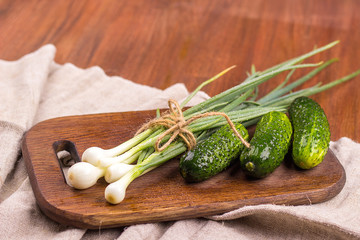 young green onion, young green cucumber on a wooden chopping boa