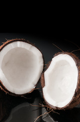 Coconut broken in half on a black background