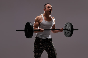 Determined young athlete exercising with a barbell