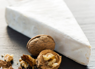 Brie cheese with walnut on a stone background