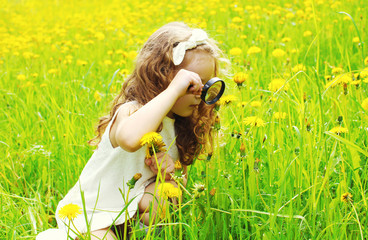 Little girl child looking through a magnifying glass on yellow d