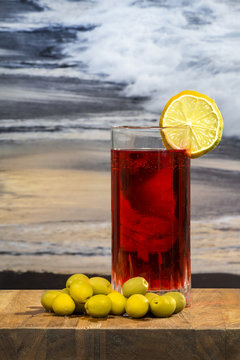 glass of vermouth with olives on a wood table