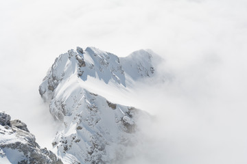 Fototapeta na wymiar vschneiter Berg sticht aus Nebelmeer hervor