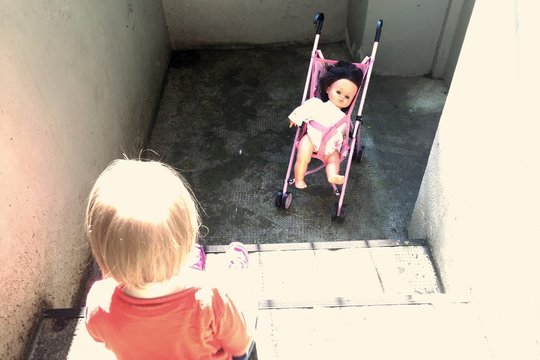 Kleinkind mit Puppenwagen