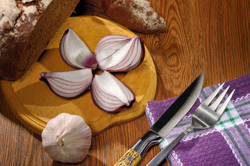  .bread black head of garlic and onion halves knife and fork