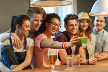 happy friends with smartphone taking selfie at bar