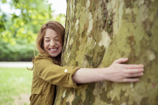 lachende frau umarmt einen baum