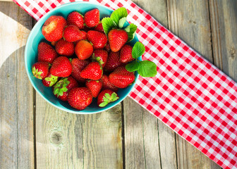 Strawberries in a paper bag on an old wooden background.