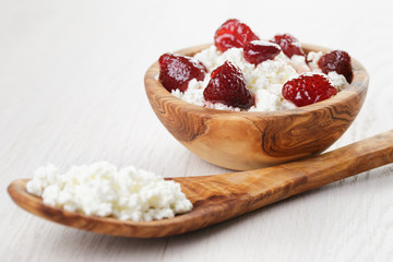 cottage cheese with preserved strawberry in wood bowl on oak