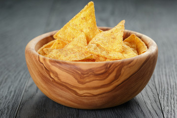 tortilla chips in olive wood bowl on wooden table
