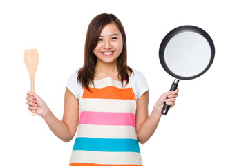 Housewife holding up with frying pan and wooden ladle