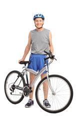 Fototapeta premium Senior biker standing behind a bicycle and smiling