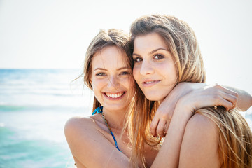 Beach in summer. A couple of young women in swimwear hugging affectionately in the sun on a summer...