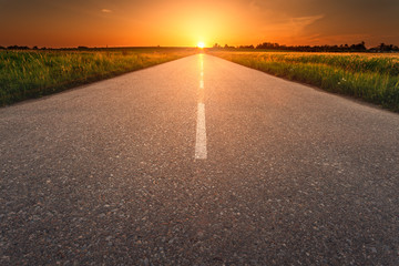 Driving on an empty asphalt road at sunset