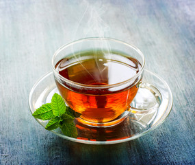 Hot cup of tea with mint leaf on dark rustic background