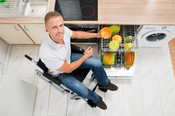 Disabled Man Arranging Plate In Dish Rack