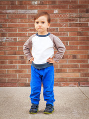 Toddler boy by brick wall laughing