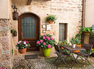 Ingresso romantico di casa con mobili da giardino e vasi di fiori