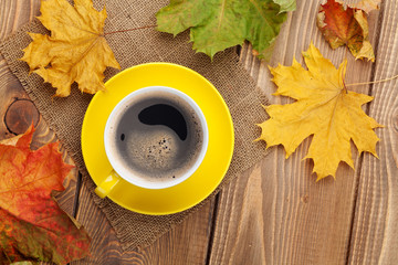 Autumn leaves and coffee cup over wood background