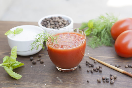 Tomato juice, tomatos, herbs and spices on wooden table 