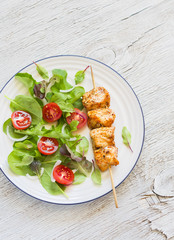 chicken kebab on a wooden skewer and fresh vegetable salad 
