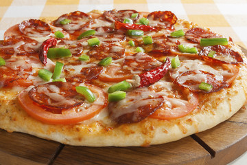 Pizza with sausage and hot peppers on a wooden board.