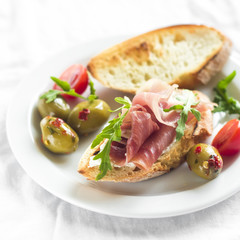 delicious appetizer to wine - toast with ham, olives and cherry tomatoes