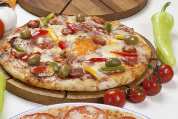 Pizza with several kinds of meat products, mushrooms and cheese served on a table.